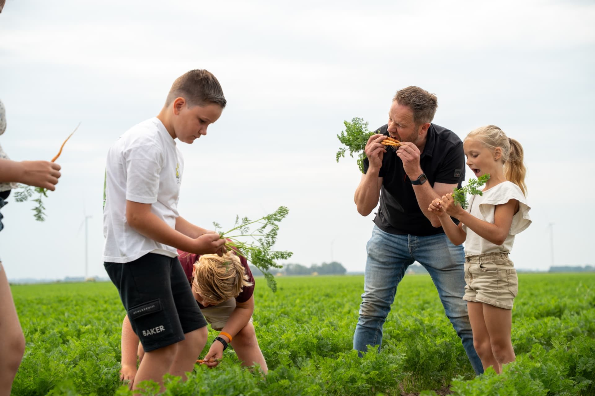 Leerlingen en boer proeven wortels op het land